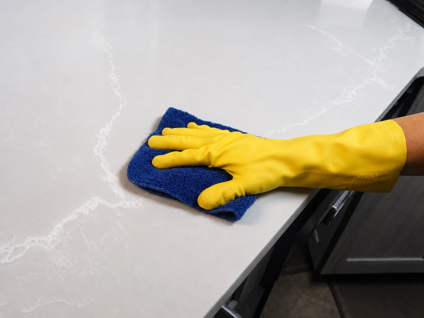 ClearView cleaning a countertop with a blue cloth and yellow glove